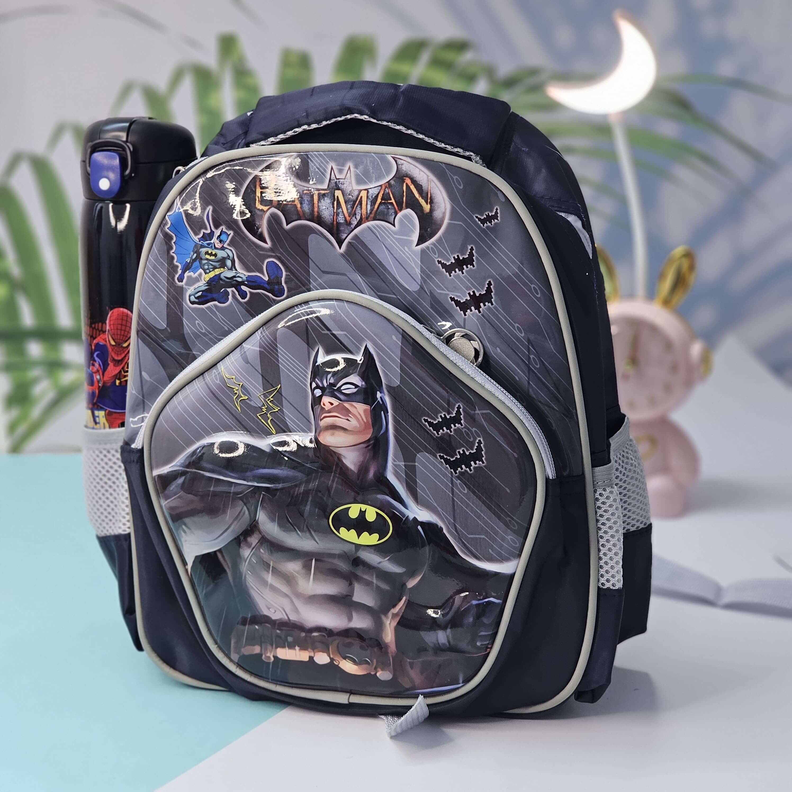 Batman-themed backpack on a light blue surface with a blurred background